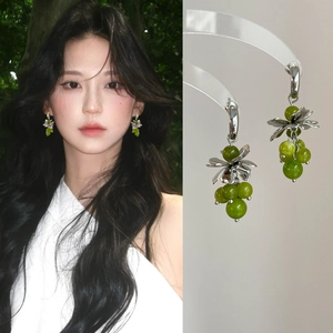 Detail showing green crystal grape cluster earrings and model wearing C-shaped tassels