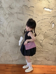 Pink sequin crossbody bag with silver chain strap worn by a young girl model