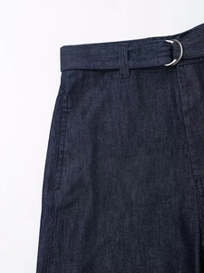 Détail de la taille d'un jean bleu foncé avec ceinture assortie et boucle métallique en D