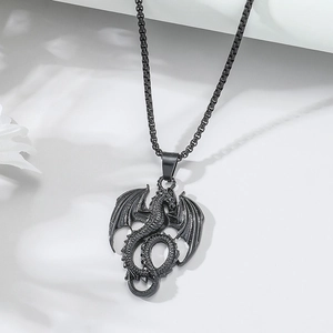 Close-up of black flying dragon pendant with detailed box chain on marble background