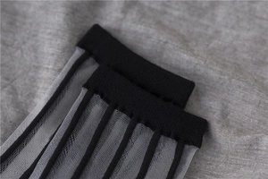 Detail of sheer black vertical stripe mesh socks with wide ribbed cuff texture