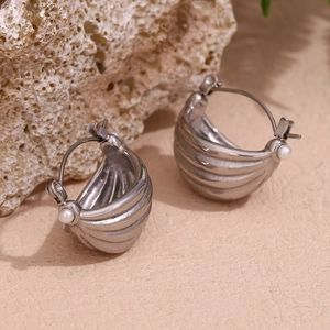 Detailed close-up of textured silver boat-shaped earring with pearl on coral stone