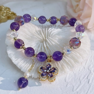 Detailed close-up of natural amethyst bracelet with flower charm and pearl on coral