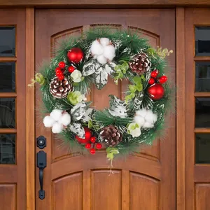 Christmas pine needle wreath with pine cones and red ornaments on a wooden door