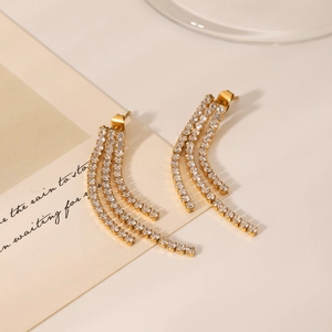 Close-up of golden triple-row tassel earrings with sparkling white zircons and stones