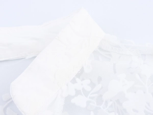 Detailed macro view of white sheer mesh fabric with delicate floral lace embroidery