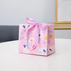 Pink starry sky paper gift bag with silk ribbon bow and woven handles for celebrations