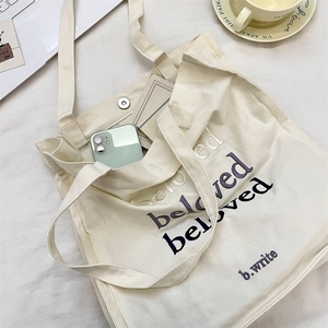 Detail of canvas tote bag with beloved embroidery, showing magnetic closure and interior space