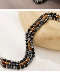 Detailed close-up of multi-layer beaded bracelet with black lava stone and tiger eye beads