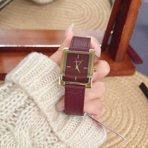 Detail of vintage square gold watch with burgundy leather strap on a woman wrist