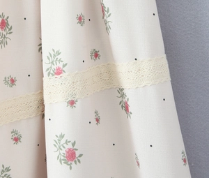 Close-up of floral print fabric with lace trim and pink rose patterns on cream base
