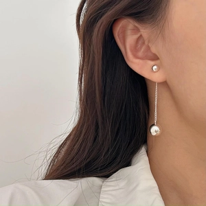 Detail of silver long tassel earrings with polished round spheres on a female model