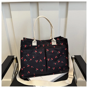 Detail of cherry print canvas tote bag featuring two front pockets and woven handles