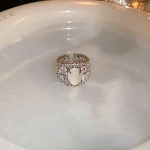 Macro shot of silver oval opal ring with zircon pavé on a white ceramic tray