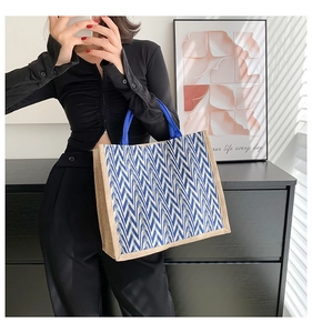Detail of blue and white wavy stripe woven tote bag with navy circular handles
