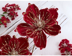 Detail of red velvet Christmas flower with golden glitter edges on white wooden tray