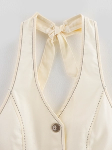 Détail du gilet dos nu crème avec surpiqûres noires et texture de tissu en coton mélangé