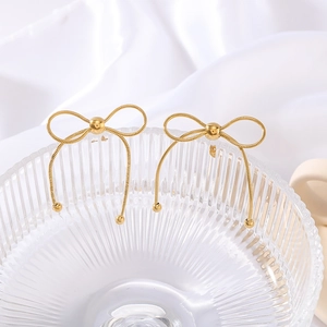 French style gold plated bow earrings displayed in a glass bowl on white silk