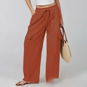 Detail of rust red wide-leg cargo pants with elastic drawstring waist and large side pockets