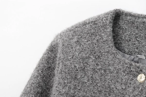 Détail de veste grise en bouclé avec bouton métallique lion et texture de tissu premium
