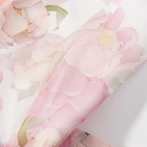 Detail of floral printed organza fabric with soft pink peonies and green leaves