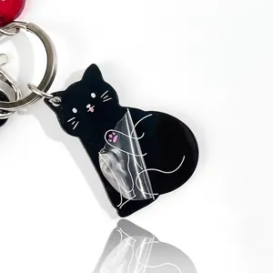 Creative black cat acrylic keychain with spring coil and protective film on white background