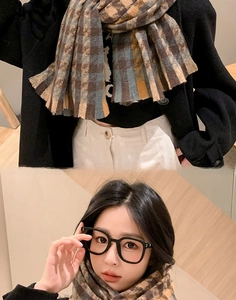 Détail d'une écharpe en maille pied-de-poule gris et jaune avec un manteau noir chic