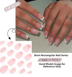Detail of pink French gradient press-on nails with white bows and sparkling rhinestones