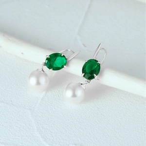 Macro view of S925 silver pearl earrings with oval green emerald gemstone details
