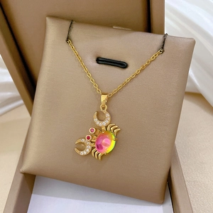 Macro shot of gold-plated crab pendant with rainbow gemstones and diamond accents