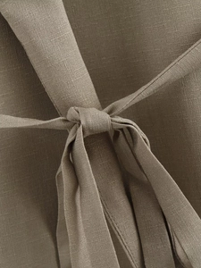 Macro shot of texture fabric and tie-knot design detail on a brown two-piece set