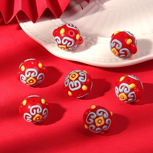 Detailed view of red handcrafted ceramic beads with traditional blue cloud patterns for DIY