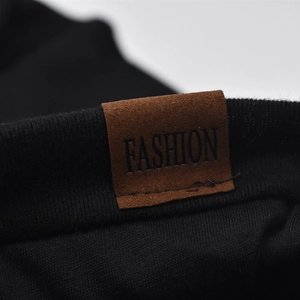 Detailed macro view of black knitted cotton fabric with a brown faux leather Fashion tag