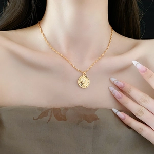 Close-up of a gold ethnic beaded necklace featuring a vintage round relief pendant