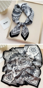 Detail of silk scarf showing black and white paisley patterns and elegant smooth texture