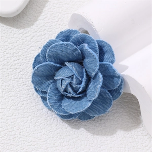 Detailed close-up of handmade blue denim camellia flower brooch with layered petals