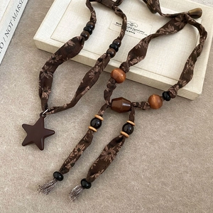 Détail d'un collier bohème en tissu floral avec perles en bois et pendentif étoile