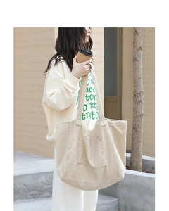 Detail of off-white corduroy tote bag showing ribbed texture and front pocket design