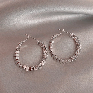 Macro detail of silver circle earrings with metallic discs and sparkling zircon beads