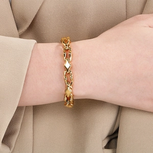 Close-up of a gold stainless steel link bracelet worn on a wrist with a beige suit