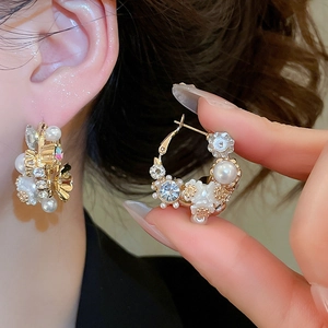 Detailed close-up of elegant flower earrings with pearls and crystals on a model