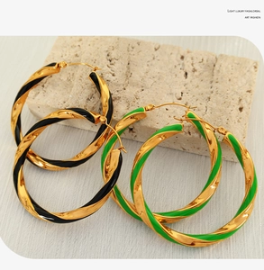Detailed view of large twisted hoop earrings with 18K gold and colorful enamel finish