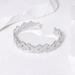 Dettaglio dei motivi a farfalla con trama spazzolata sul bracciale rigido in acciaio argento