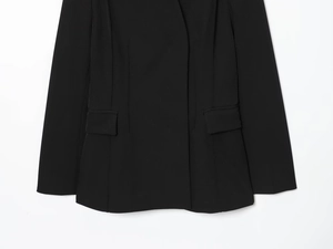 Gros plan détaillé d'un blazer noir montrant la texture du tissu tissé et les poches