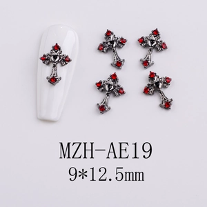 Macro view of gothic black metal cross nail charms with red rhinestones and heart detail