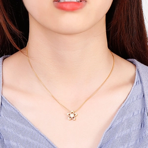 Close-up of golden hollow snowflake pendant on snake chain necklace worn by a model