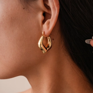 Macro view of gold geometric teardrop earrings featuring high mirror-like polish and modern style