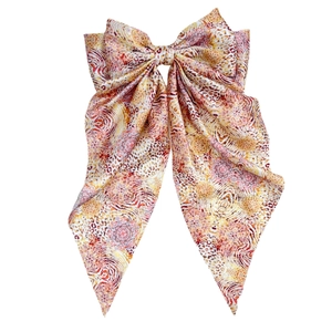 Retro print bow hair clip with long ribbons in warm tones on white background