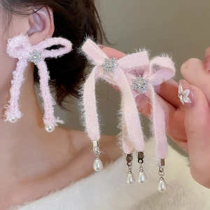 Detail of pink plush ribbon bow earrings with rhinestone snowflakes and faux pearl drops