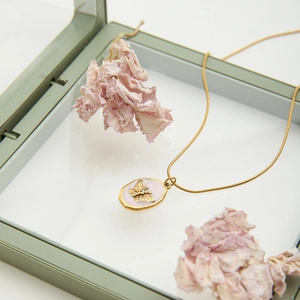 Collier en acier doré 18K avec pendentif abeille rose sur boîte à bijoux élégante